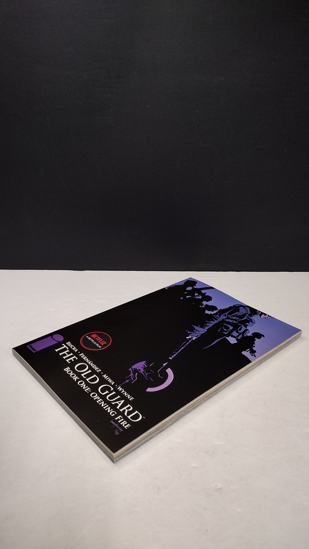(MATURE) The Old Guard Book One: Opening Fire by Greg Rucka – New Paperback (Minor Wear)