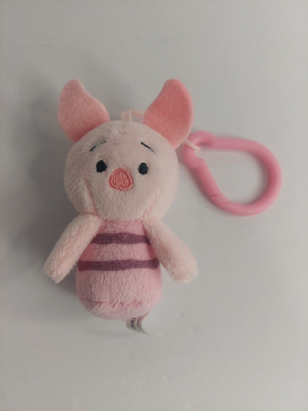 Plush pig toy with pink strap on a white background