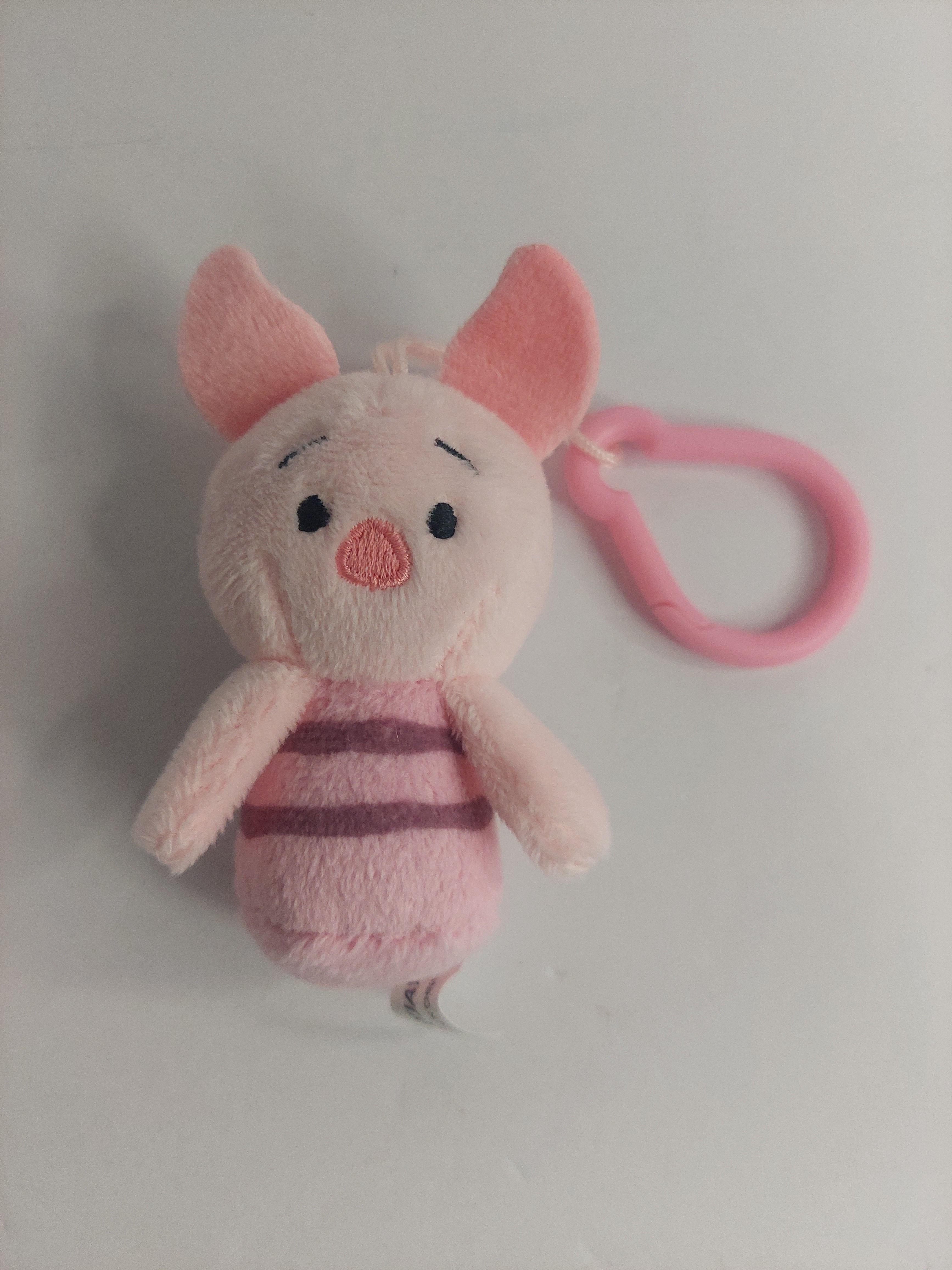 Plush pig toy with pink strap on a white background