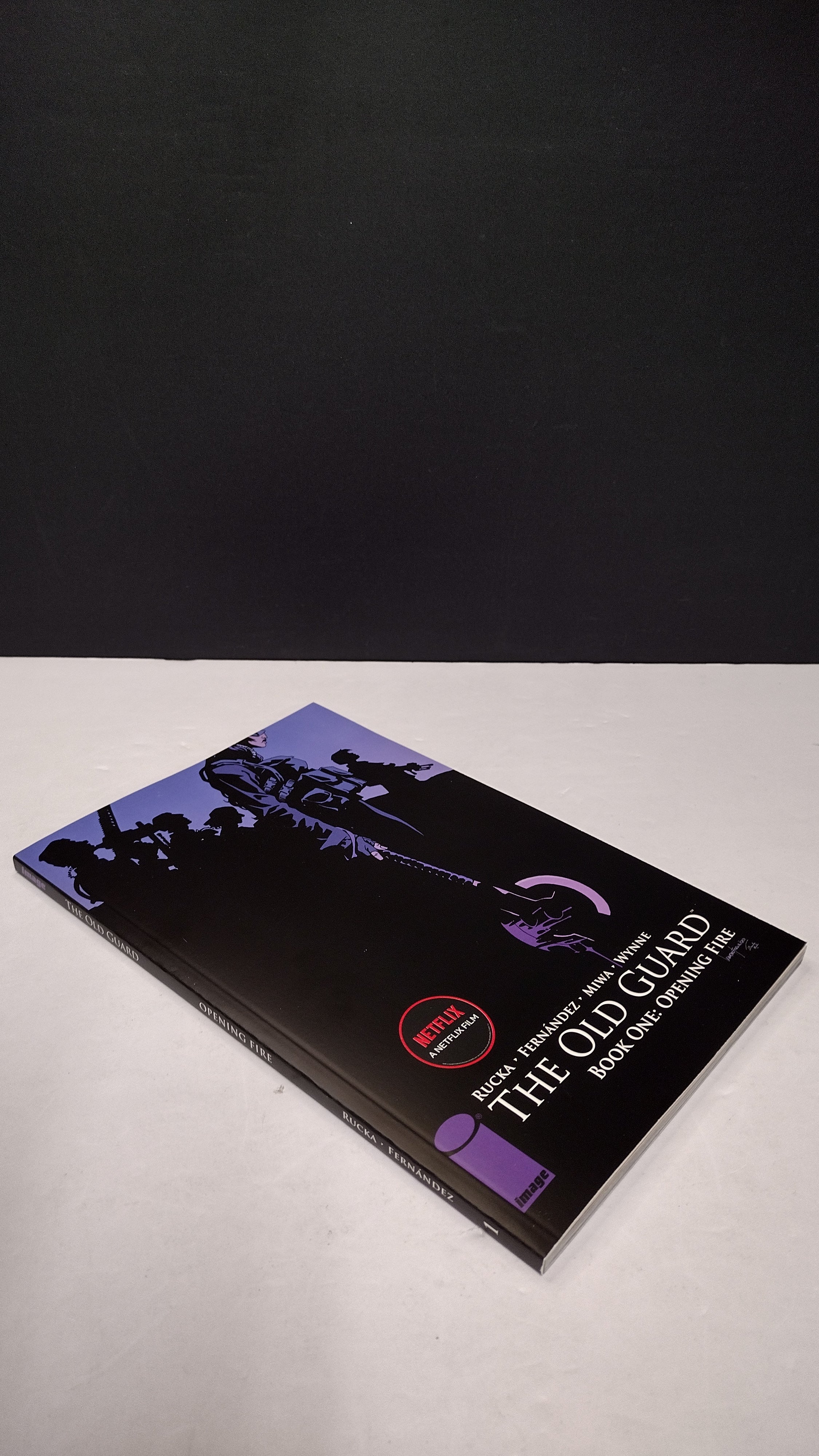 (MATURE) The Old Guard Book One: Opening Fire by Greg Rucka – New Paperback (Minor Wear)